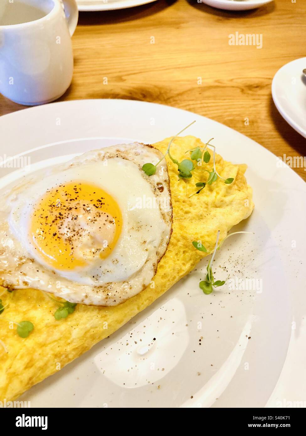 Café-Szene, Frühstücks-Omelette mit einem Spiegelei Stockfoto