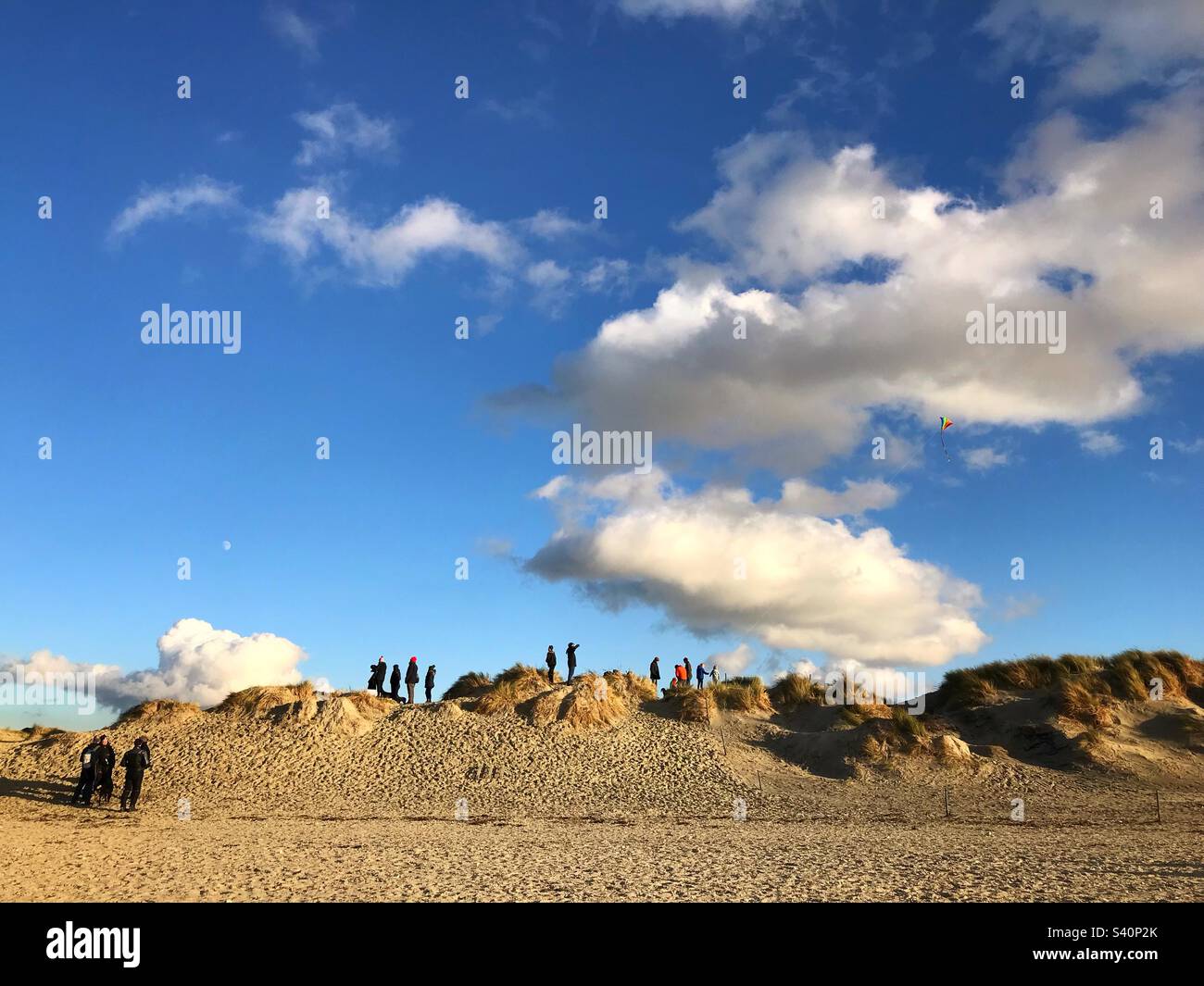 Menschen, die einen Drachen auf den Dünen bei East Head, West Wittering, West Sussex, Großbritannien, fliegen - Smartphone-aufgenommenes Stockfoto