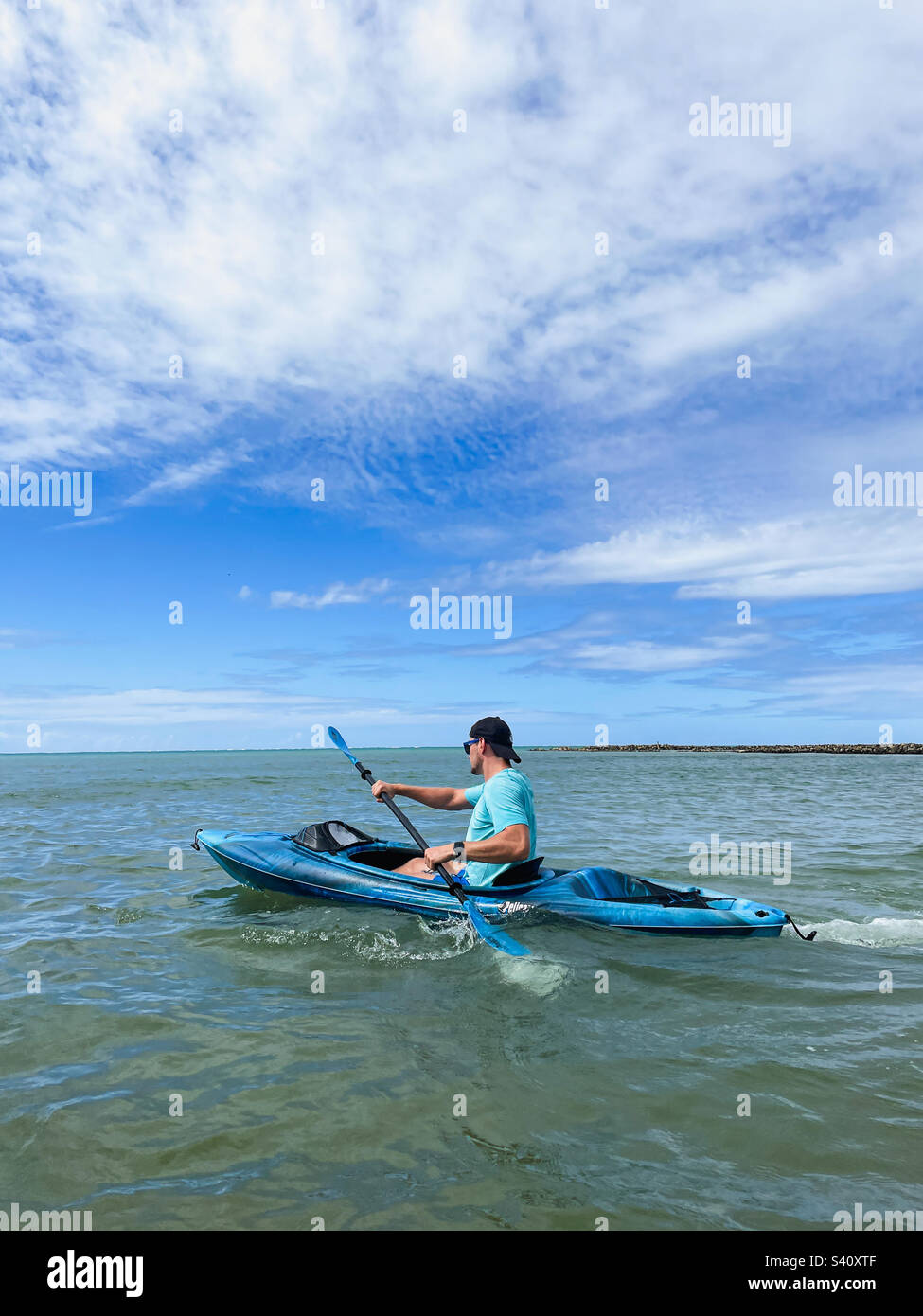 Sportlicher junger Mann, der Kajak im Meer fährt Stockfoto
