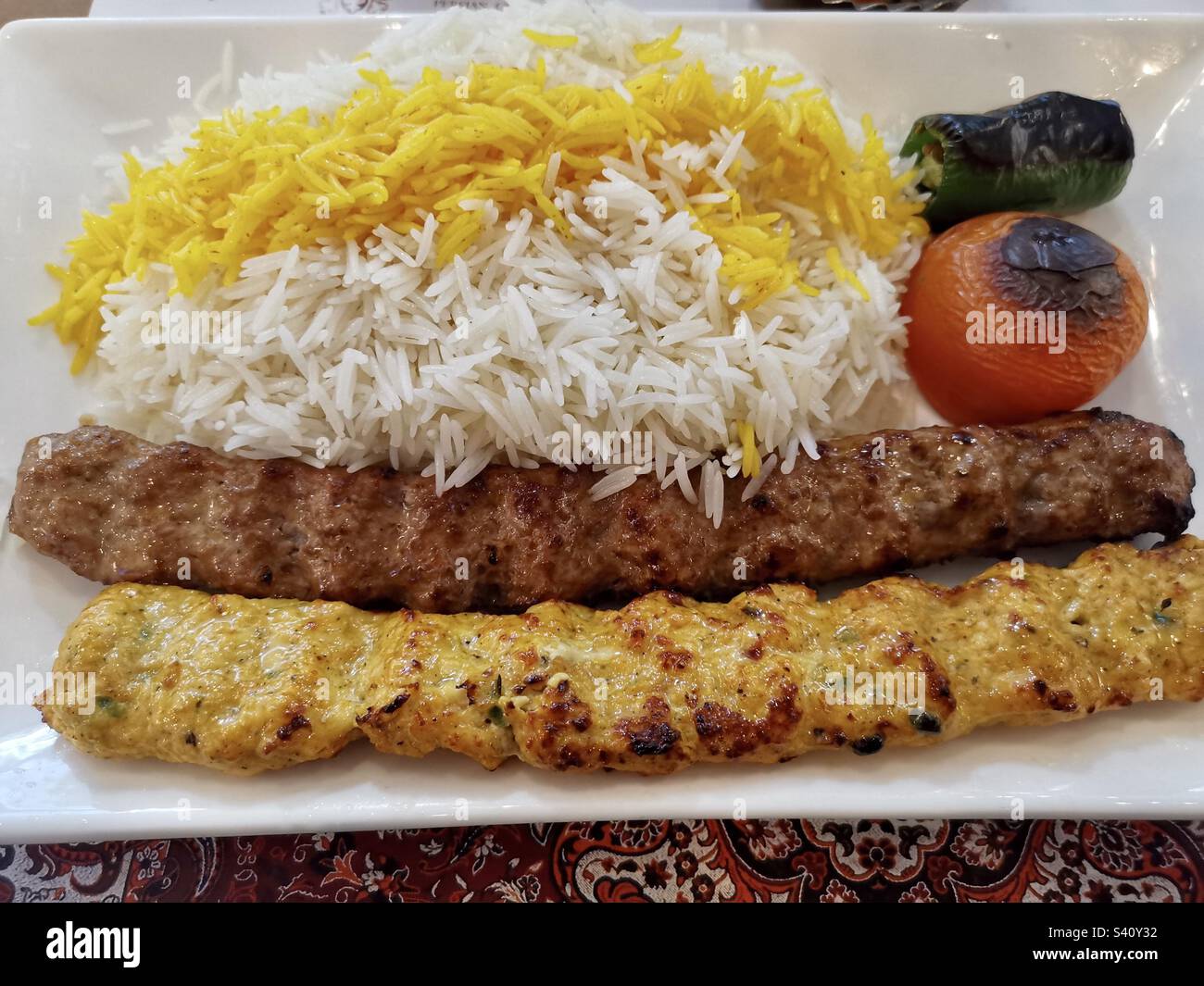 Ein Teller mit Huhn und Lamm Koobideh Kabob serviert mit persischem Reis und gerösteter Vegetation. Stockfoto