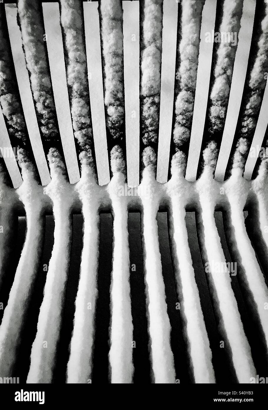 Abstrakte Aufnahme einer schneebedeckten Parkbank aus Stahl. - Smartphone-aufgenommenes Stockfoto