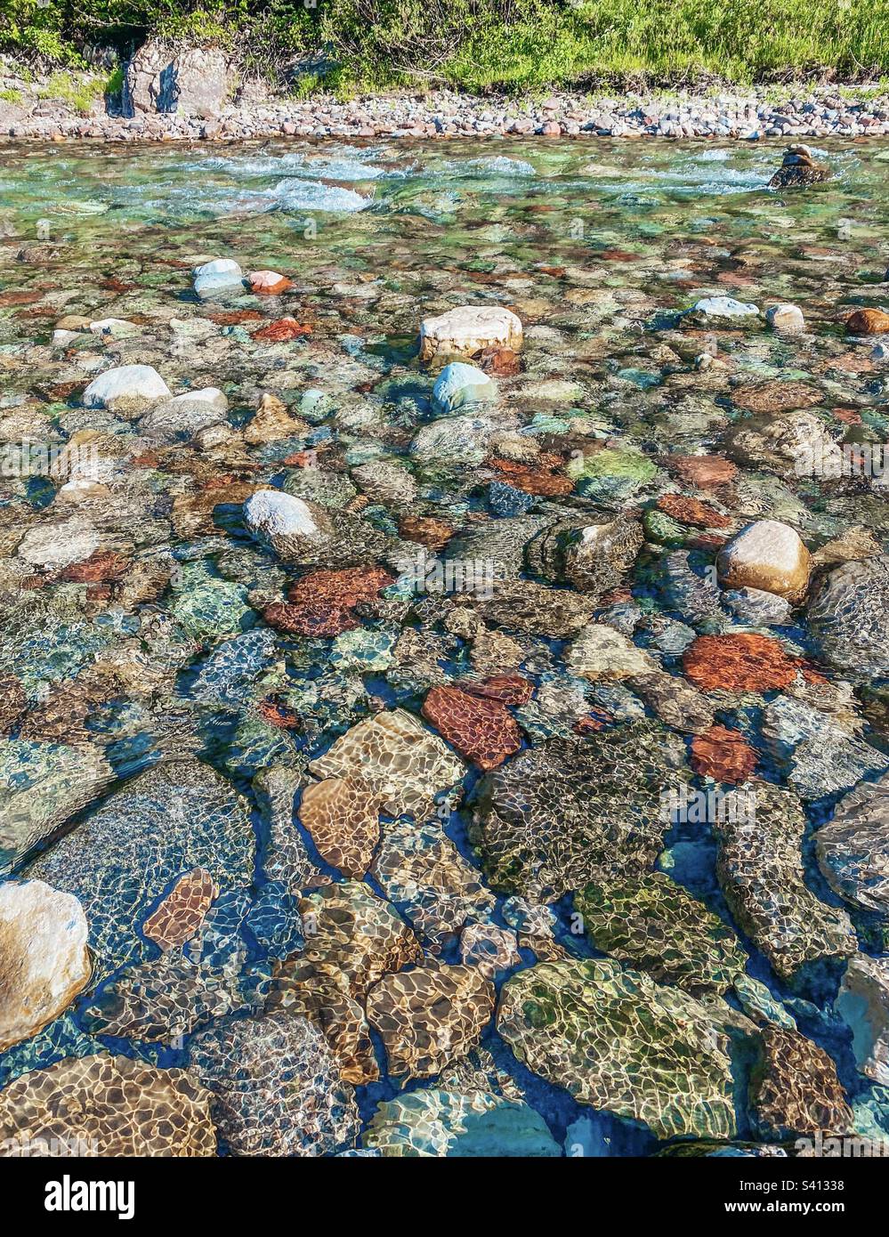 Farbenfrohe Felsen in einem Bach mit klarem Wasser, das über sie läuft Stockfoto