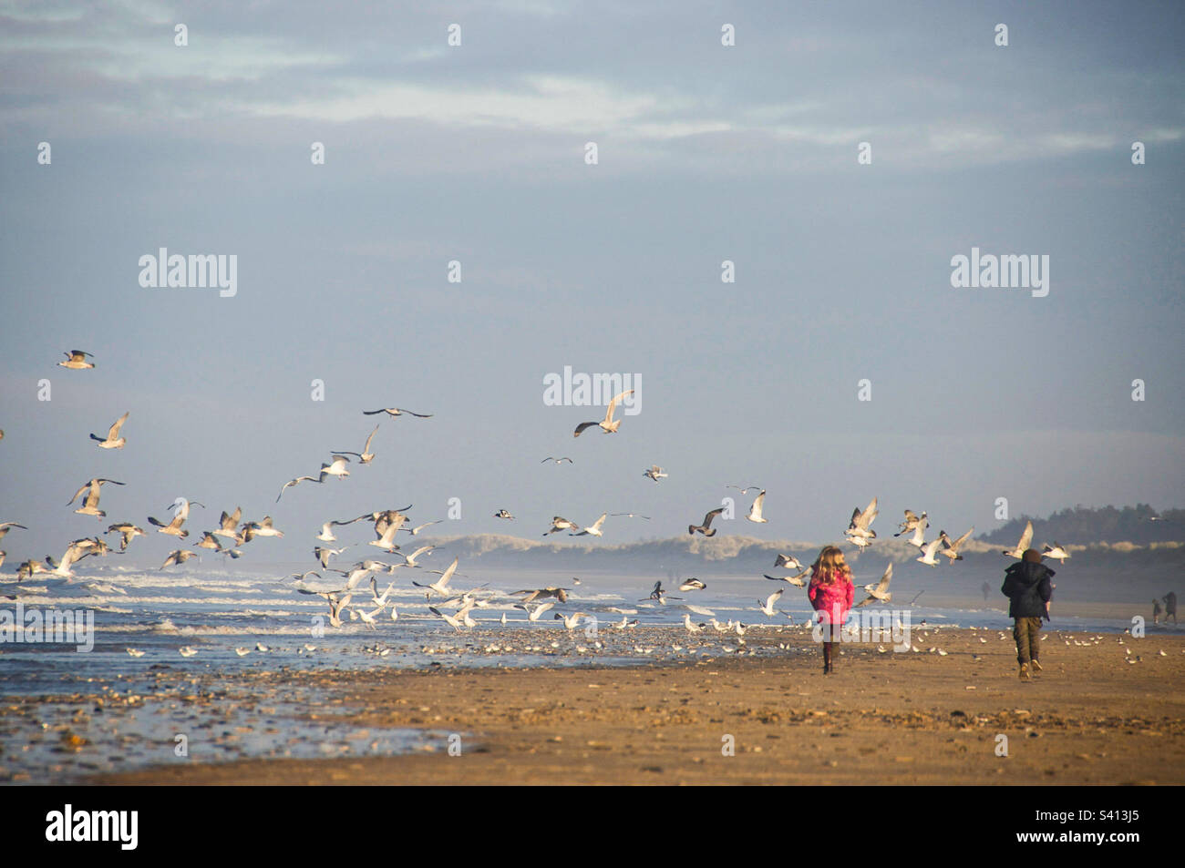 Zwei Kinder laufen am Holkham Beach in North Norfolk entlang Stockfoto