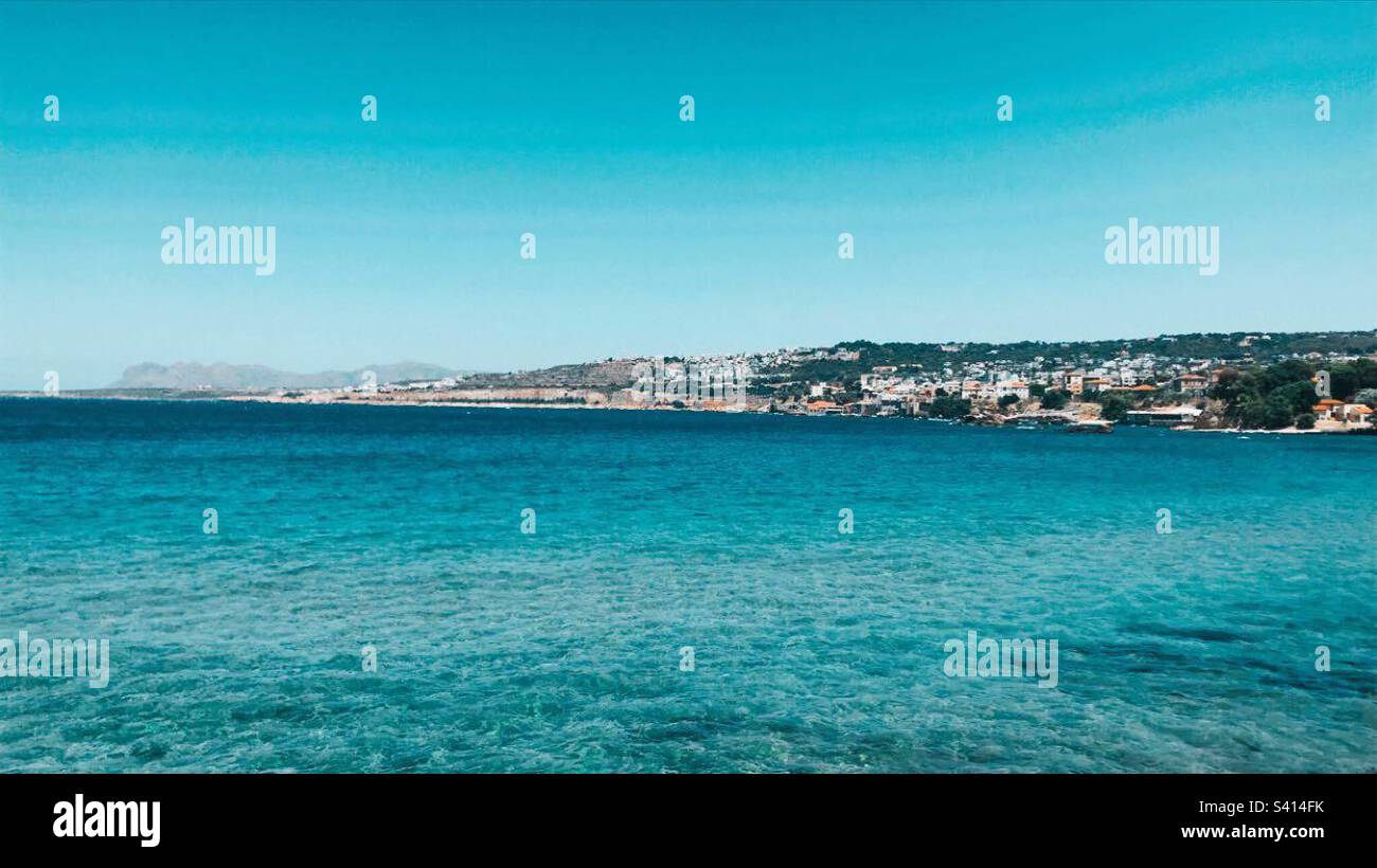 Blaues Meerwasser mit Land im Hintergrund. Klarer blauer Himmel. Stockfoto