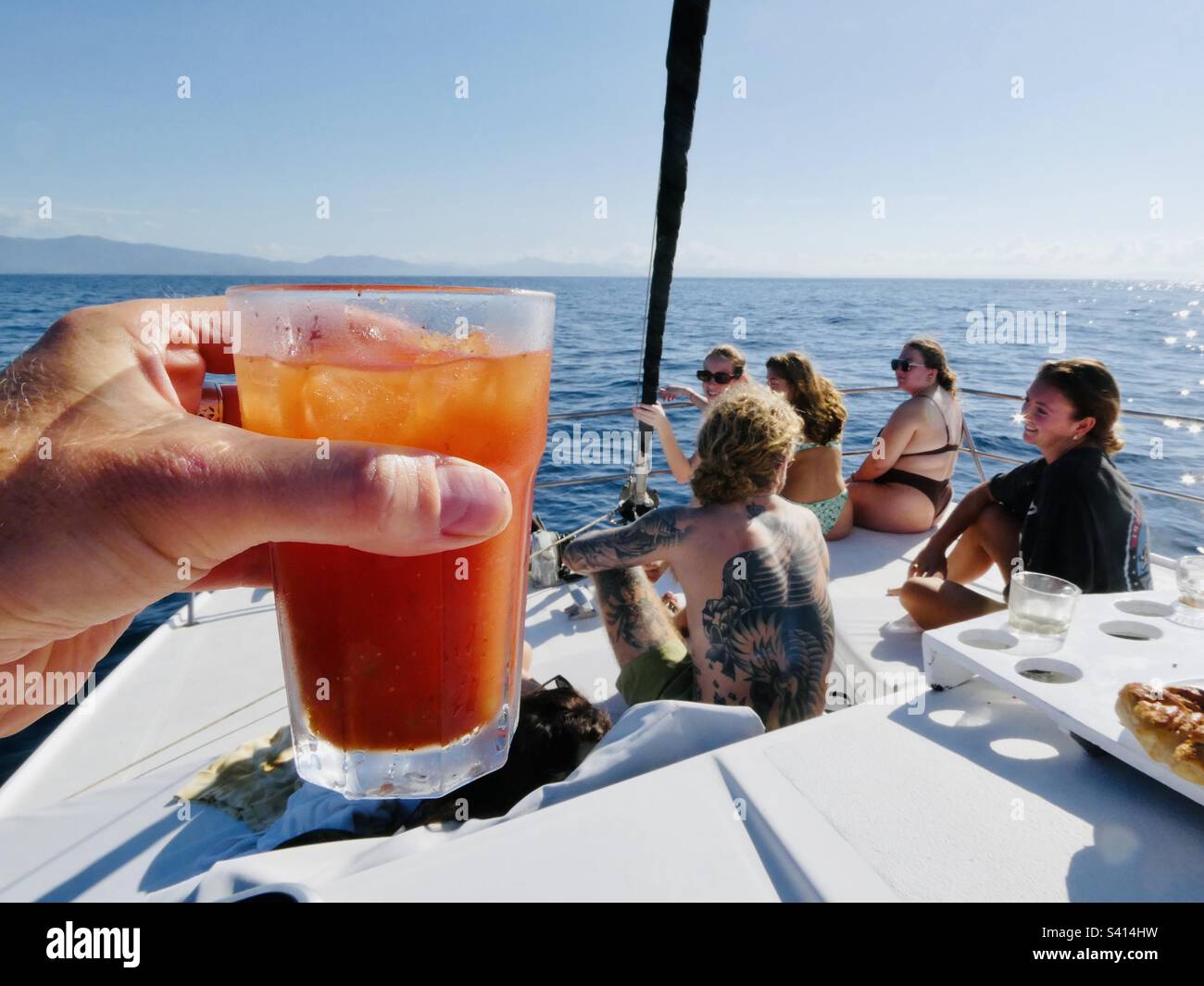 Eine Hand hält ein Bloody mary Getränk auf dem Deck eines Touristenboots, das entlang der Küste von Costa Rica fährt Stockfoto