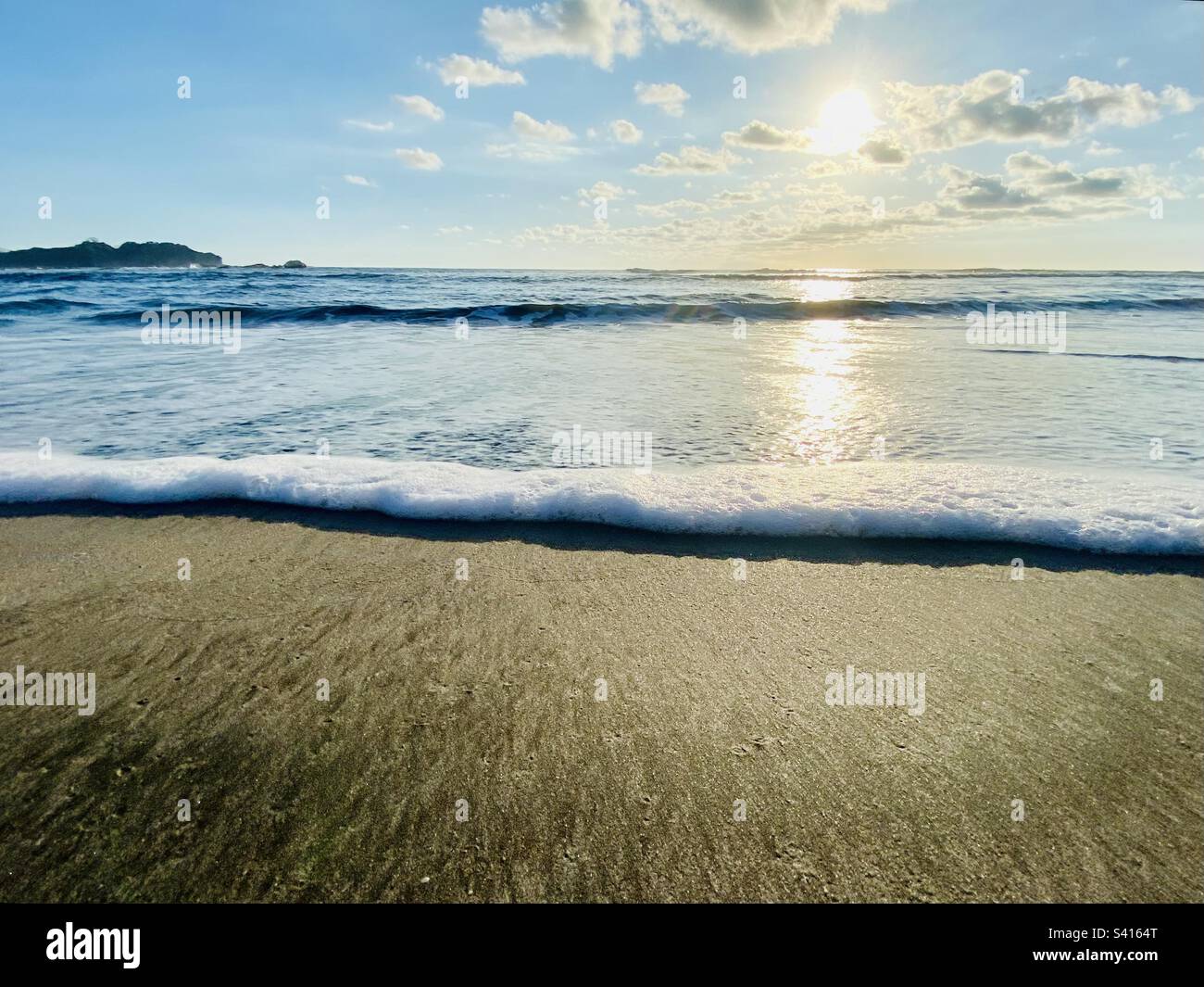 Kleine Wellen und weißes Wasser spülen sich auf den Sand an einem Strand in Nosara in Costa Rica - Smartphone-aufgenommenes Stockfoto