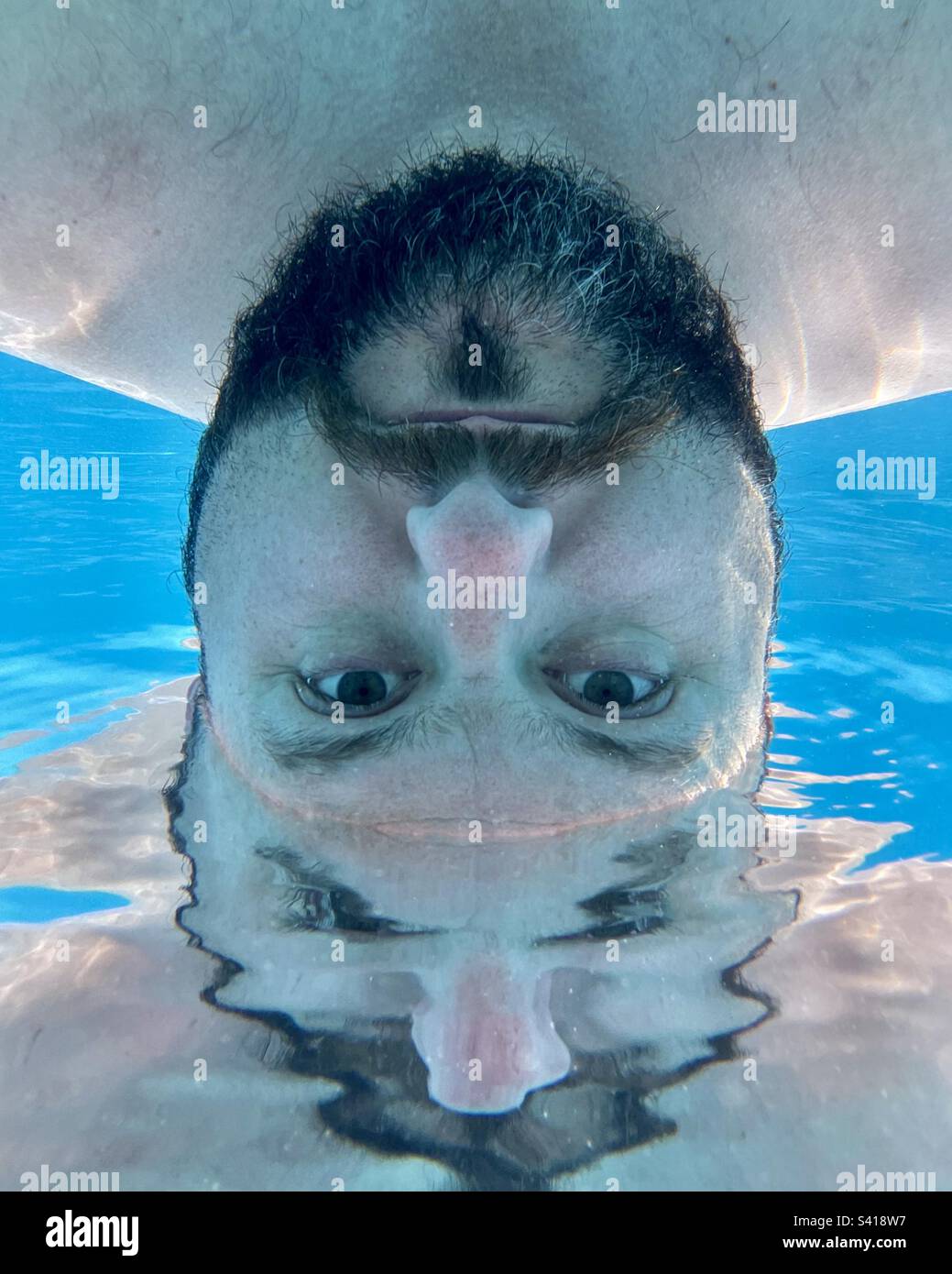 Abstraktes Unterwasserfoto eines bärtigen Mannes im Swimmingpool. Stockfoto