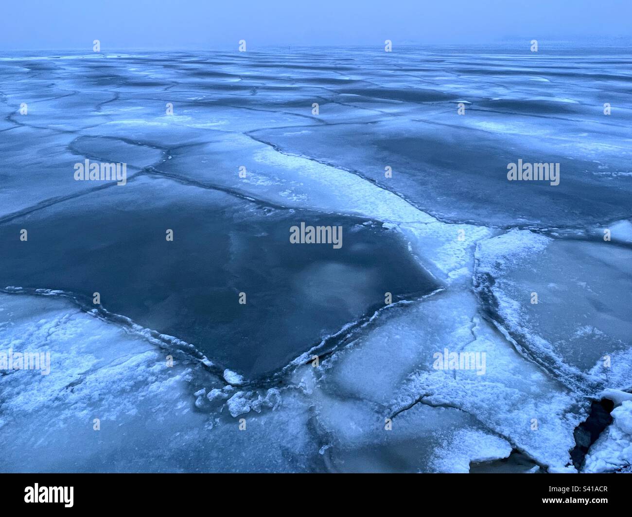 Raue Landschaft, endloses Feld mit gerissenen Eisschollen über der Ostsee - Smartphone-aufgenommenes Stockfoto