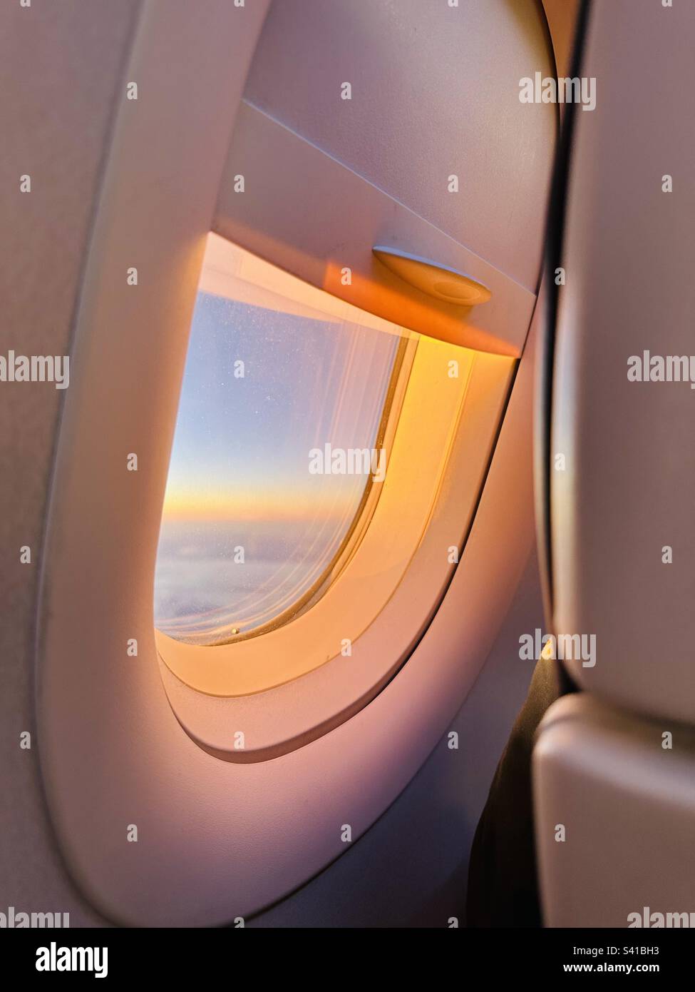 Sonnenuntergang durch das Fenster eines Flugzeugs Stockfoto