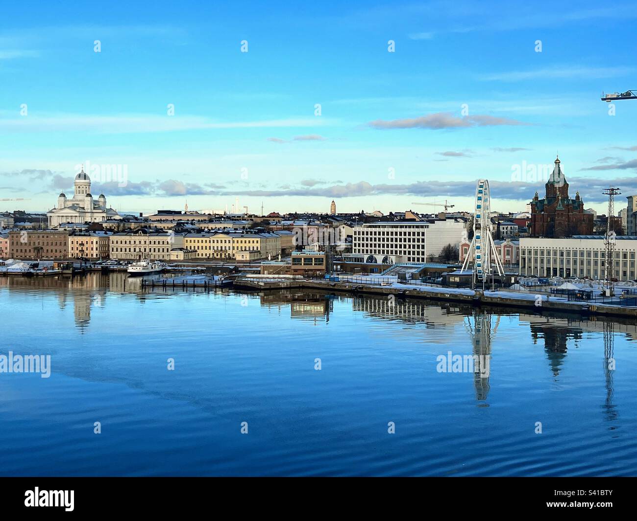 Wunderschöner Blick auf Helsinki mit Tuomiokirkko-Kirche, Uspensky-Kathedrale und Riesenrad mit Reflexion im Wasser an einem hellen Wintertag Stockfoto
