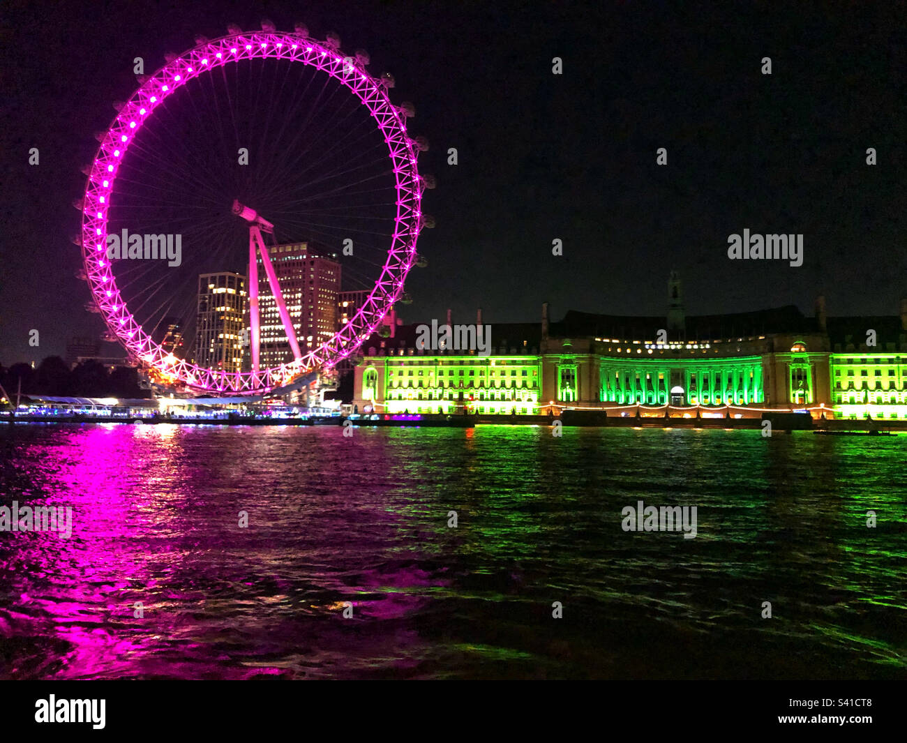 Das London Eye bei Nacht in Lila und die County Hall in Grün Stockfoto
