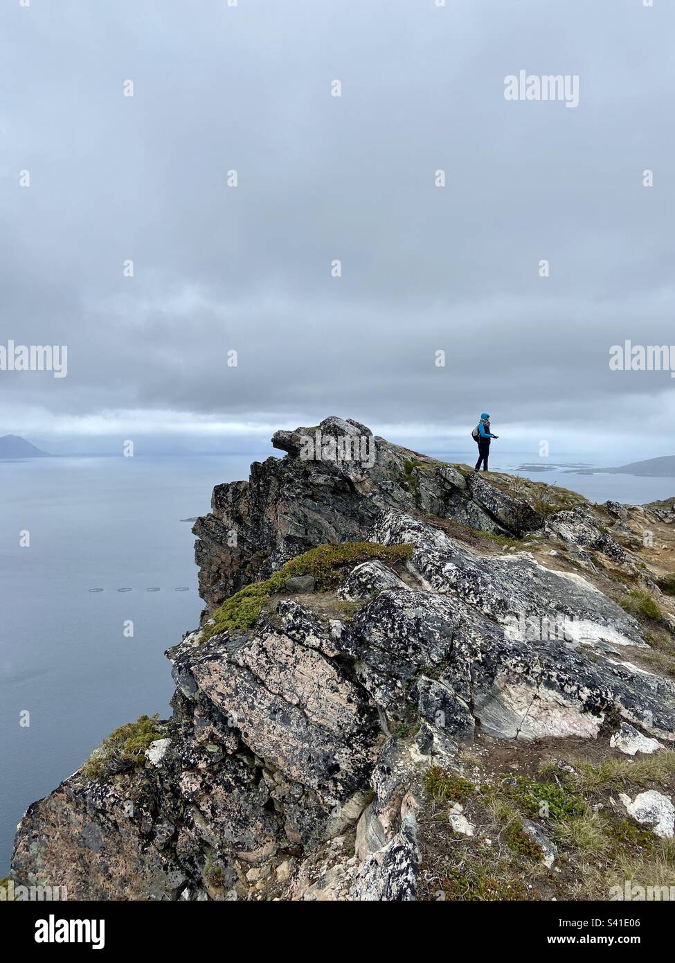 Auf dem Gipfel des Berges Keipen auf den Lofoten-Inseln, Norwegen. Lohnende Wanderung mit guter Aussicht vom Gipfel in alle Richtungen. Wanderer stehen, es gibt auch leichten Regen, der von den Wolken kommt. Stockfoto