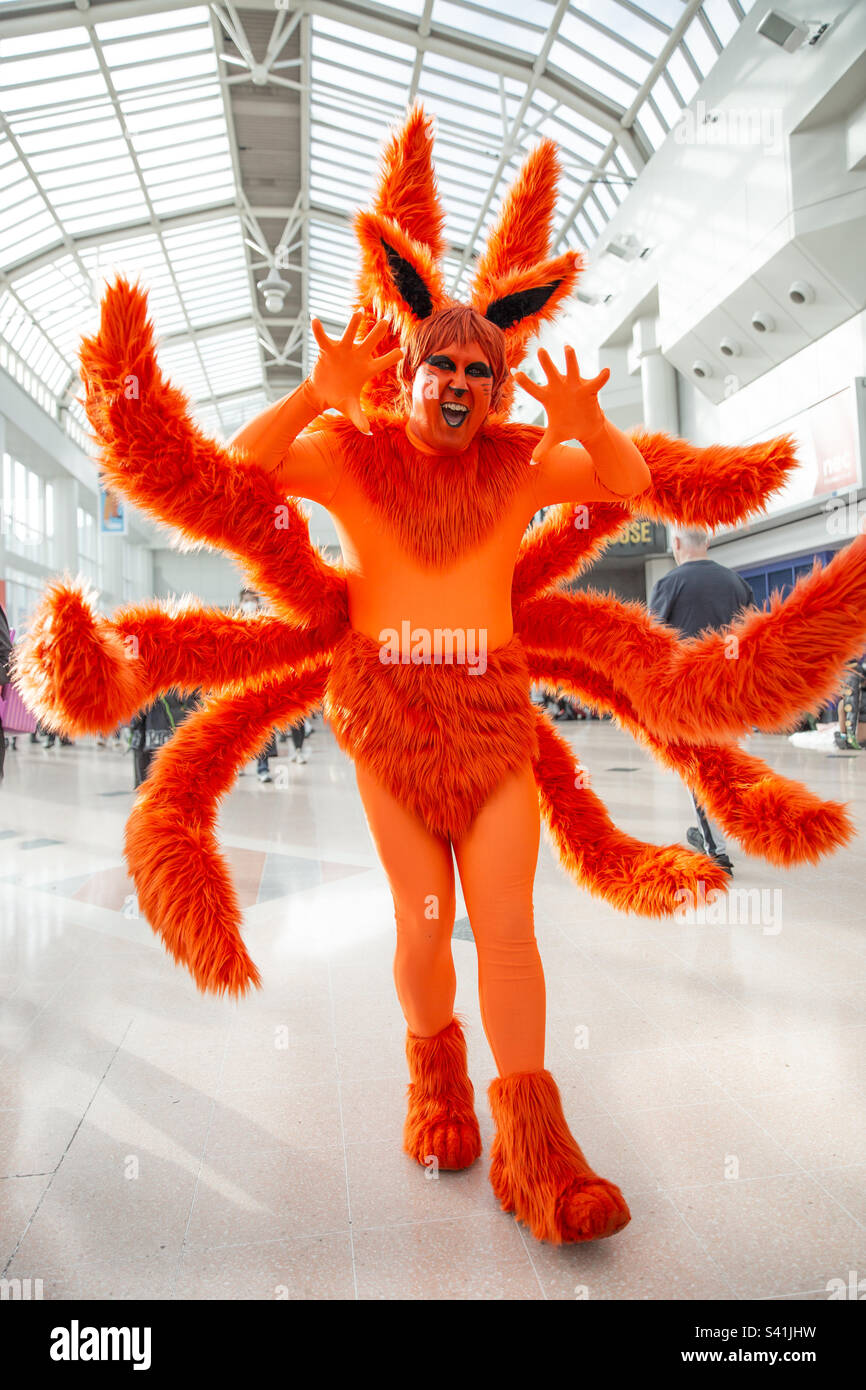 Ein männlicher Cosplayer, der lustige Gesichter in einem farbenfrohen orangefarbenen Kreatur-Kostüm bei einer Comic-Hochstaplerveranstaltung macht Stockfoto