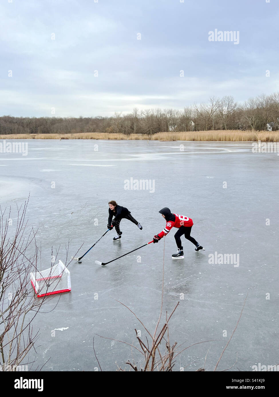 Zwei Jungs spielen Eishockey auf einem gefrorenen Teich in New Jersey, USA. Stockfoto