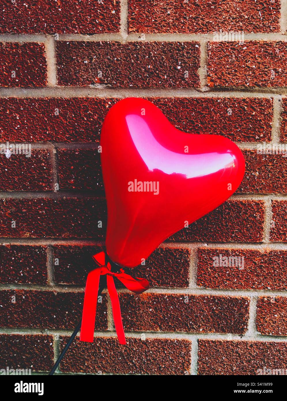 Ein roter Liebesherz-Ballon an der Wand Stockfoto