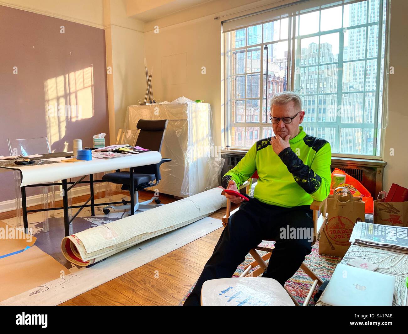 Ein erwachsener Hauseigentümer auf seinem Handy während des Chaos eines Heimwerkerprojekts in Midtown Manhattan Apartment, 2023, New York City, USA - Smartphone-aufgenommenes Stockfoto