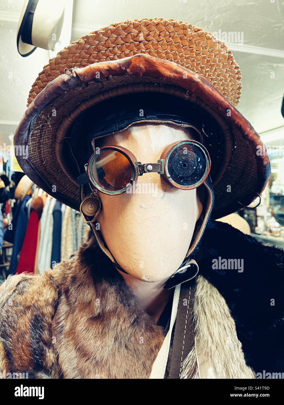 Gesichtslose Prüfpuppe mit Pilotenbrille und Vintage-Hut im Antiquitätenladen Stockfoto