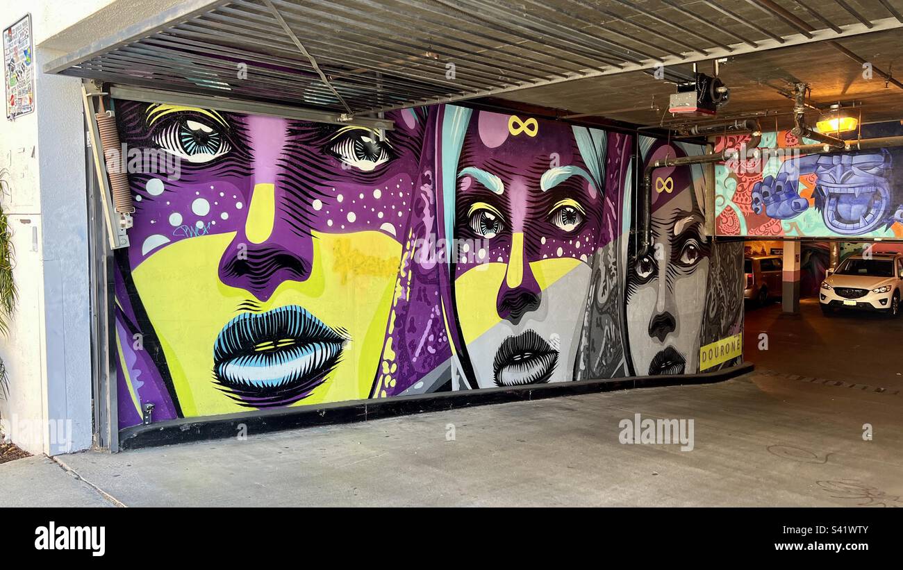 LOS ANGELES, CA, 2022. JUNI: Wunderschönes Wandgemälde mit drei Frauengesichtern an der Wand eines Garageneingangs im Melrose District Stockfoto