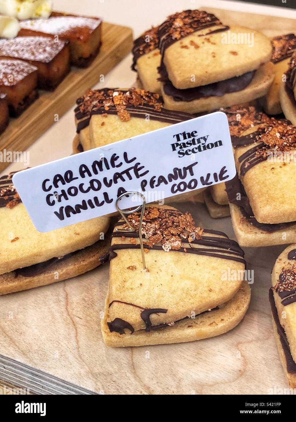 Herzförmiger Karamellschokolade-Vanille-Erdnuss-Keks im Fenster des Bäckereigeschäfts - Smartphone-aufgenommenes Stockfoto