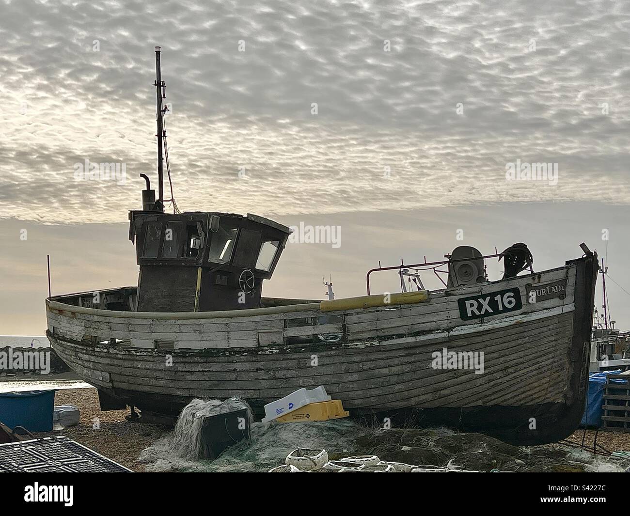 Altes hölzernes Fischerboot, das am Hastings Beach in East Sussex England gestrandet ist Stockfoto