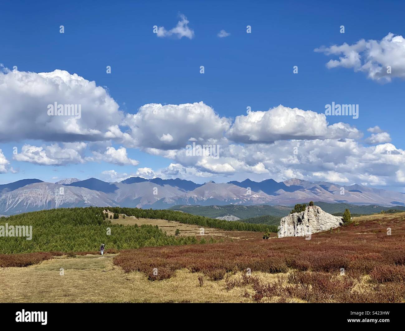 Ein Mädchen wandert auf einem Hochplateau vor dem Hintergrund von Bergen und Wolken auf einem Pfad im Altai-Gebirge. - Smartphone-aufgenommenes Stockfoto