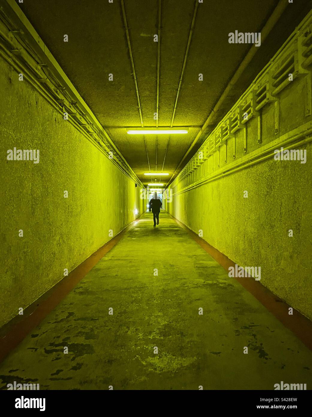 Einsame Figur im beleuchteten Tunnel - Smartphone-aufgenommenes Stockfoto