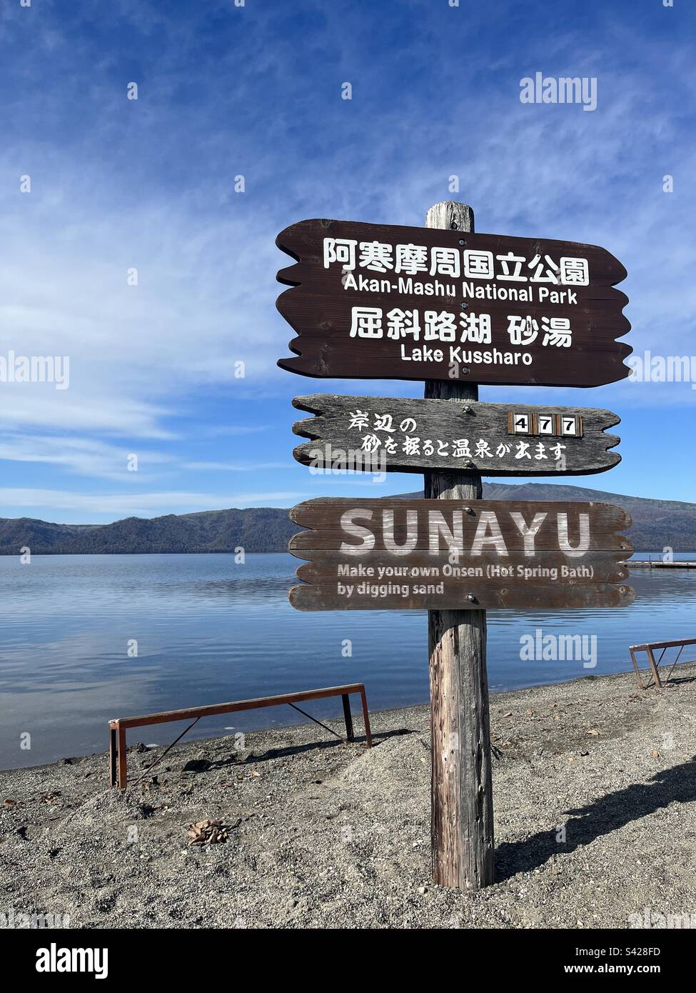 Kussharo-See und hölzernes Hinweisschild. Kawayu, Hokkaido, Japan. 11. November 2022. Japanischer Text (Mittelbrett): Es gibt 477 heiße Spa-Plätze rund um den See - Smartphone-aufgenommenes Stockfoto