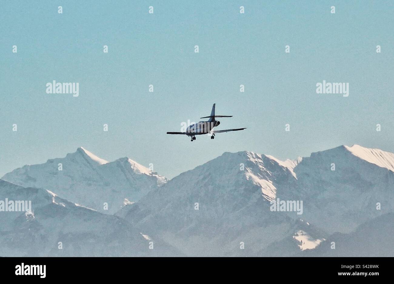 Kleines Flugzeug, das zum Flughafen Bern Belp, Schweiz, mit schneebedeckten Bergen einfliegt Stockfoto