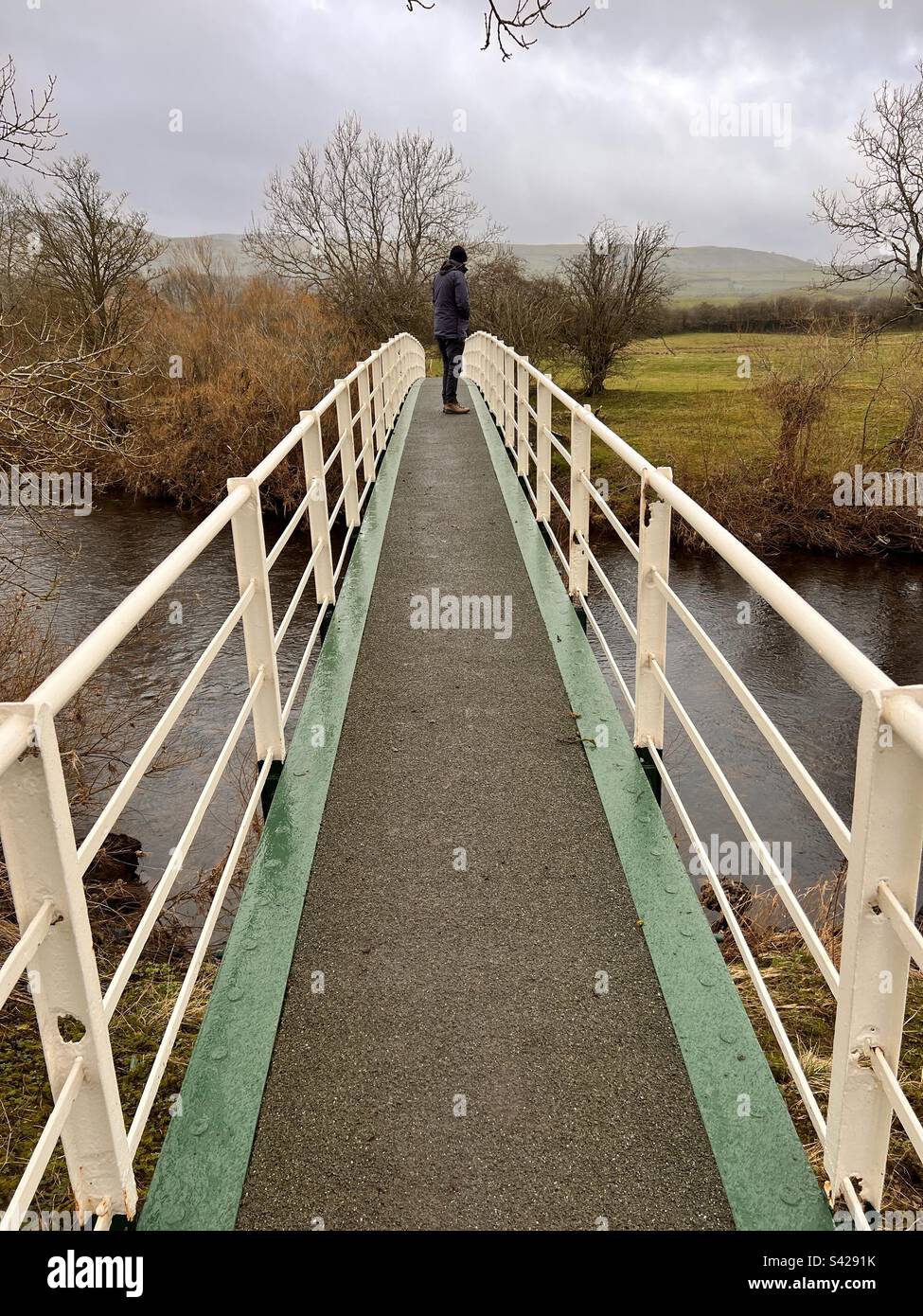 Ein Mann, der auf einer Fußgängerbrücke über dem Ure in Wensleydale steht - Smartphone-aufgenommenes Stockfoto