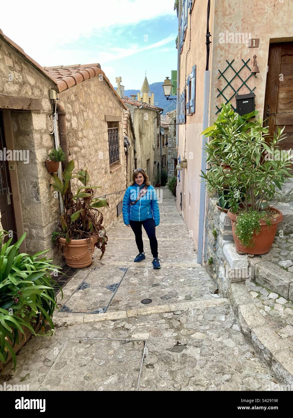 Eine Frau macht eine Pause für ein Foto und schlängelt sich durch die mittelalterliche Stadt Saint Agnes, Frankreich. Stockfoto