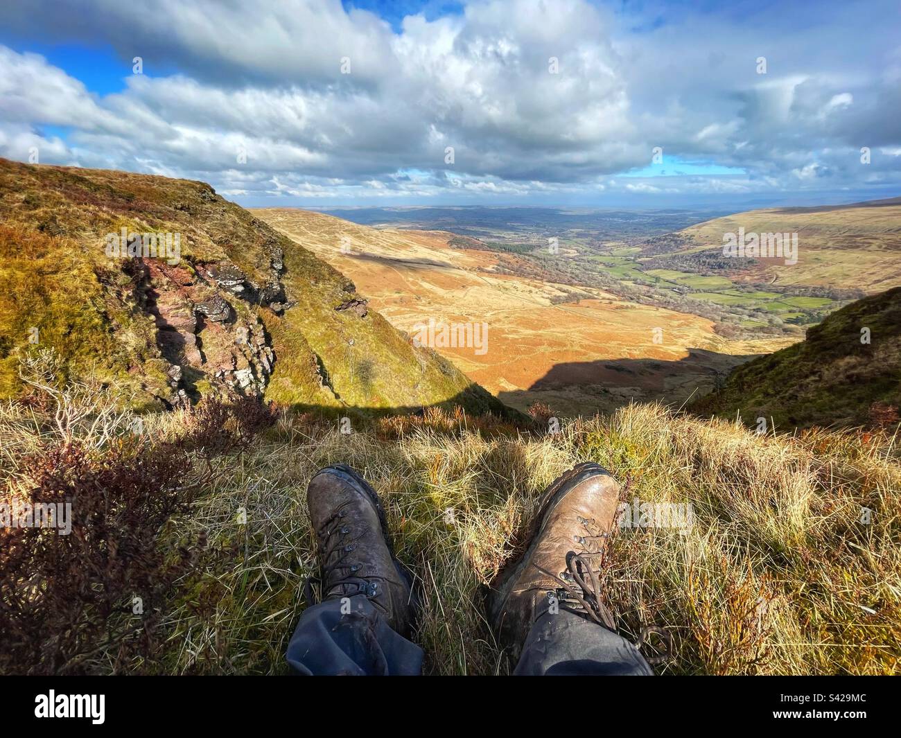 Ein Paar Beine mit Wanderstiefeln, die den Blick von Craig Cerrig Gleisiad nach Norden genießen, Brecon Beacons (Bannau Brycheniog), Wales. Stockfoto