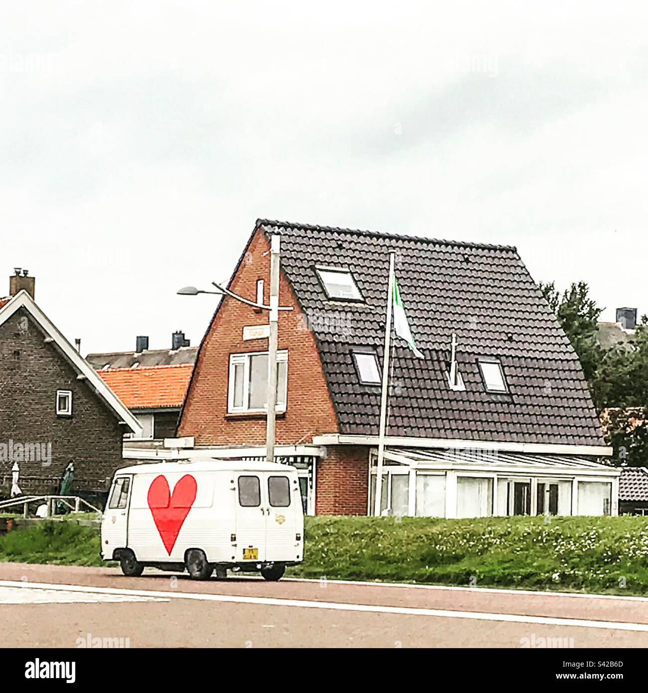Weißer Hippie-Van mit rotem Herz auf der Straße - Smartphone-aufgenommenes Stockfoto
