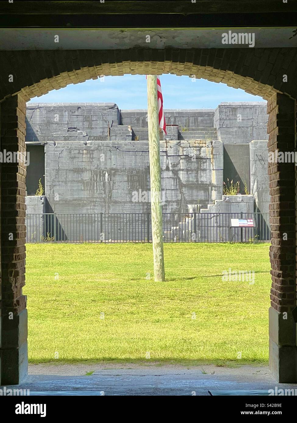 Ein Blick auf die amerikanische Flagge auf dem grünen Gras vor einer bogenförmigen Öffnung in Fort Zachary Taylor, Key West, Florida Stockfoto