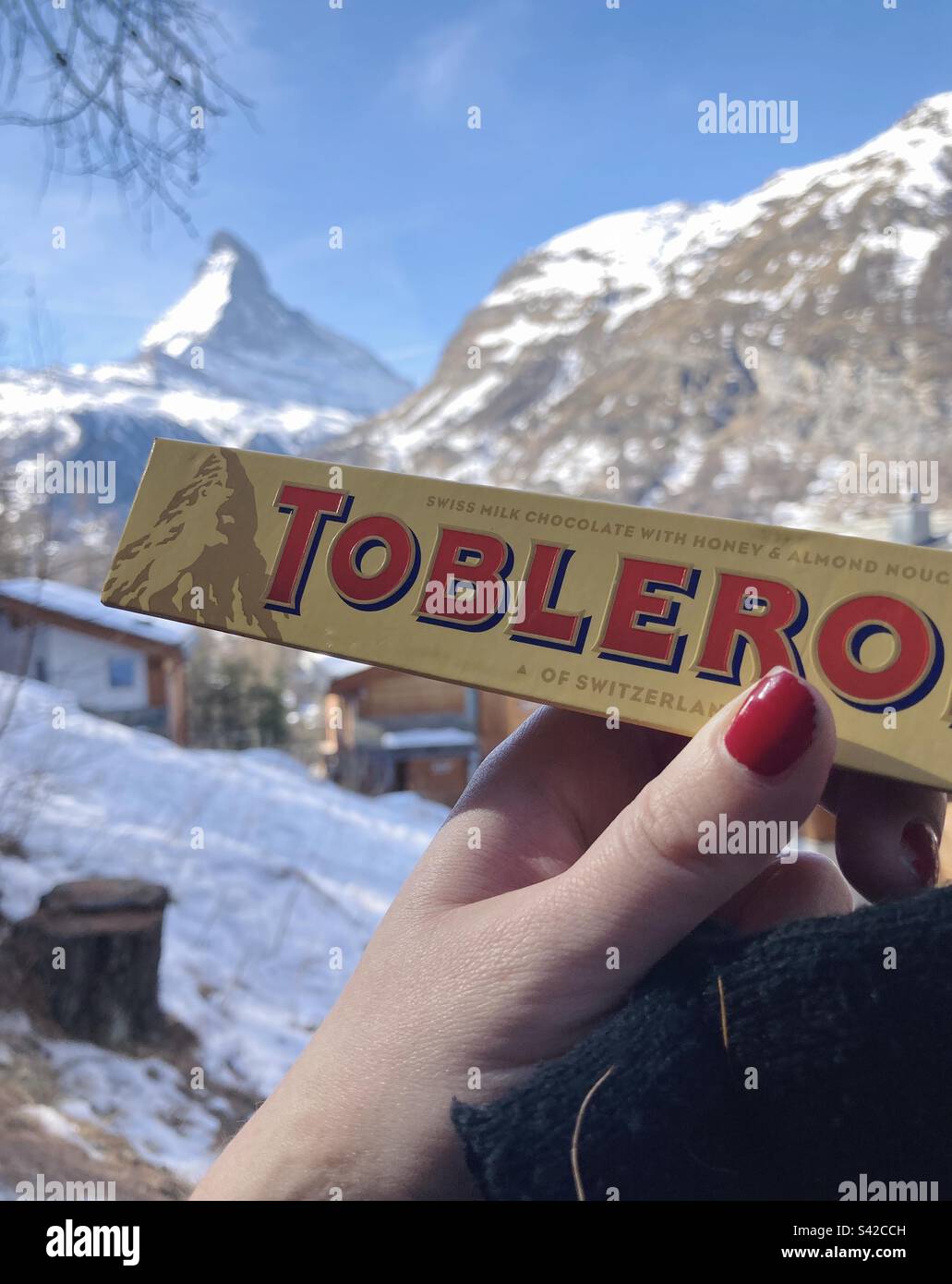 Die Toblerone Bar wird vor dem Matterhorn gehalten, das auf der Verpackung steht. Stockfoto