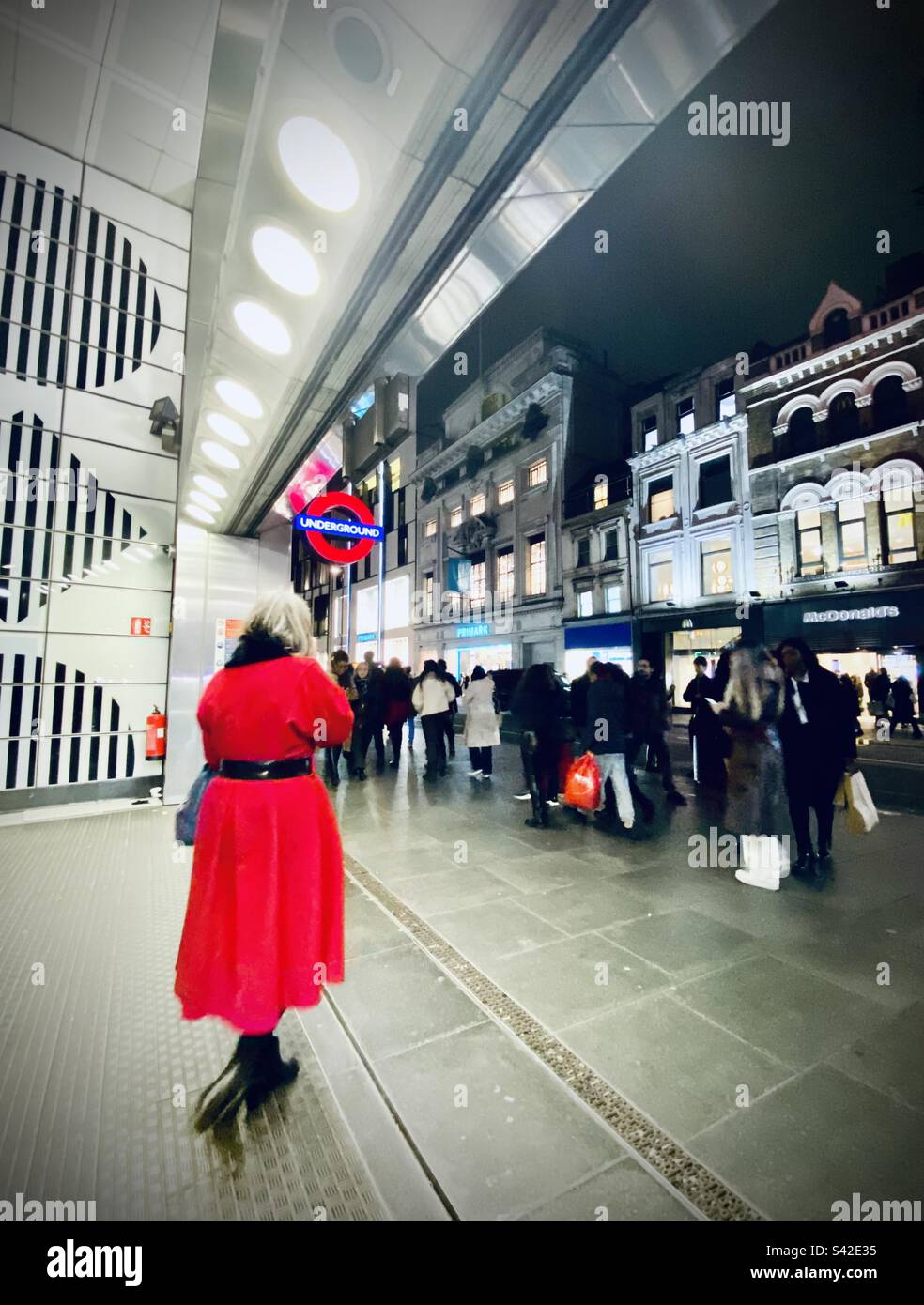 Eine Frau im roten Mantel verlässt die U-Bahn-Station in London Stockfoto