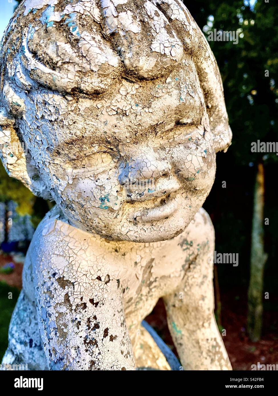 Nahaufnahme eines Mädchengesichts auf einer Zementgartstatue - Smartphone-aufgenommenes Stockfoto