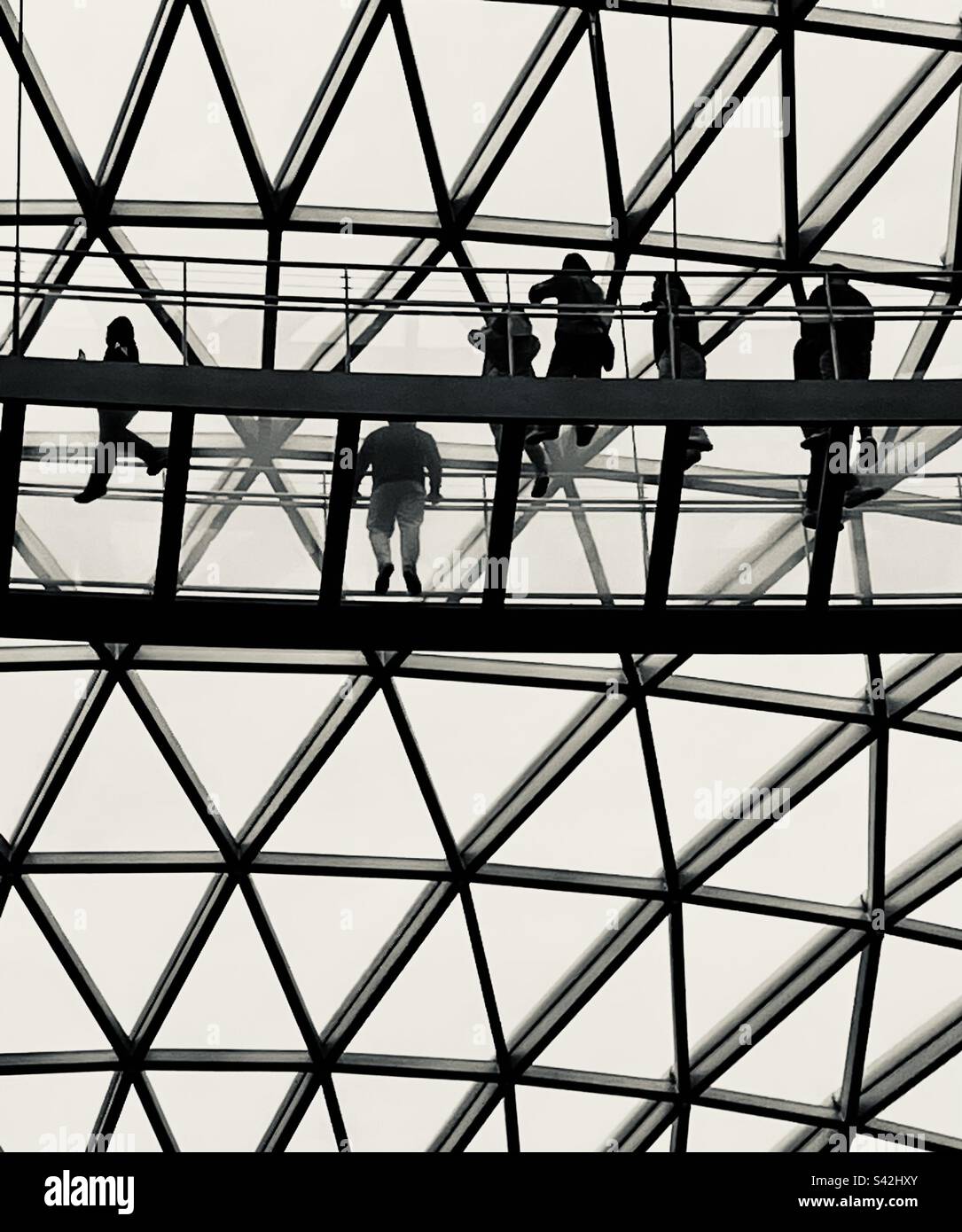 Menschen, die auf einer Glasbodenbrücke in Jewel am Changi Airport, Singapur, spazieren gehen - Smartphone-aufgenommenes Stockfoto