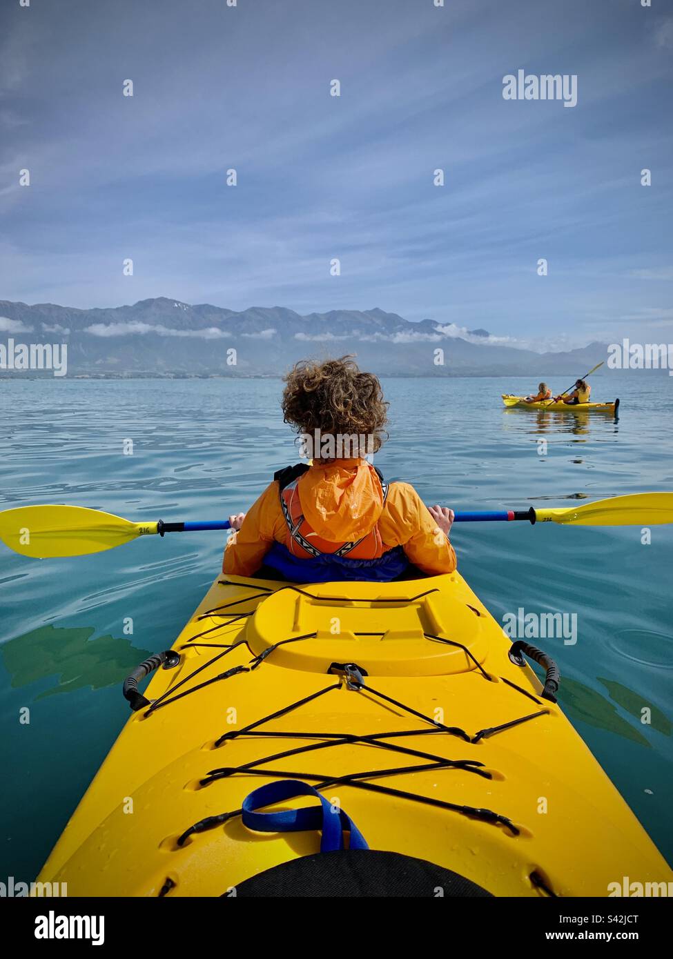 Ein Teenager in einem Doppelkajak auf einem Familienurlaub auf See vor der dramatischen Küste von Kaikoura auf der Südinsel Neuseelands Stockfoto