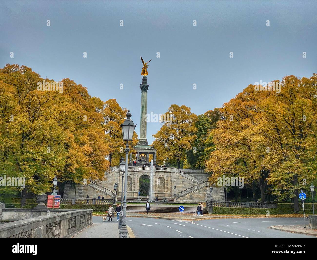 Münchner „Friedensengel“-Statue aus dem Jahr 1896, umgeben von bunten Bäumen. - Smartphone-aufgenommenes Stockfoto