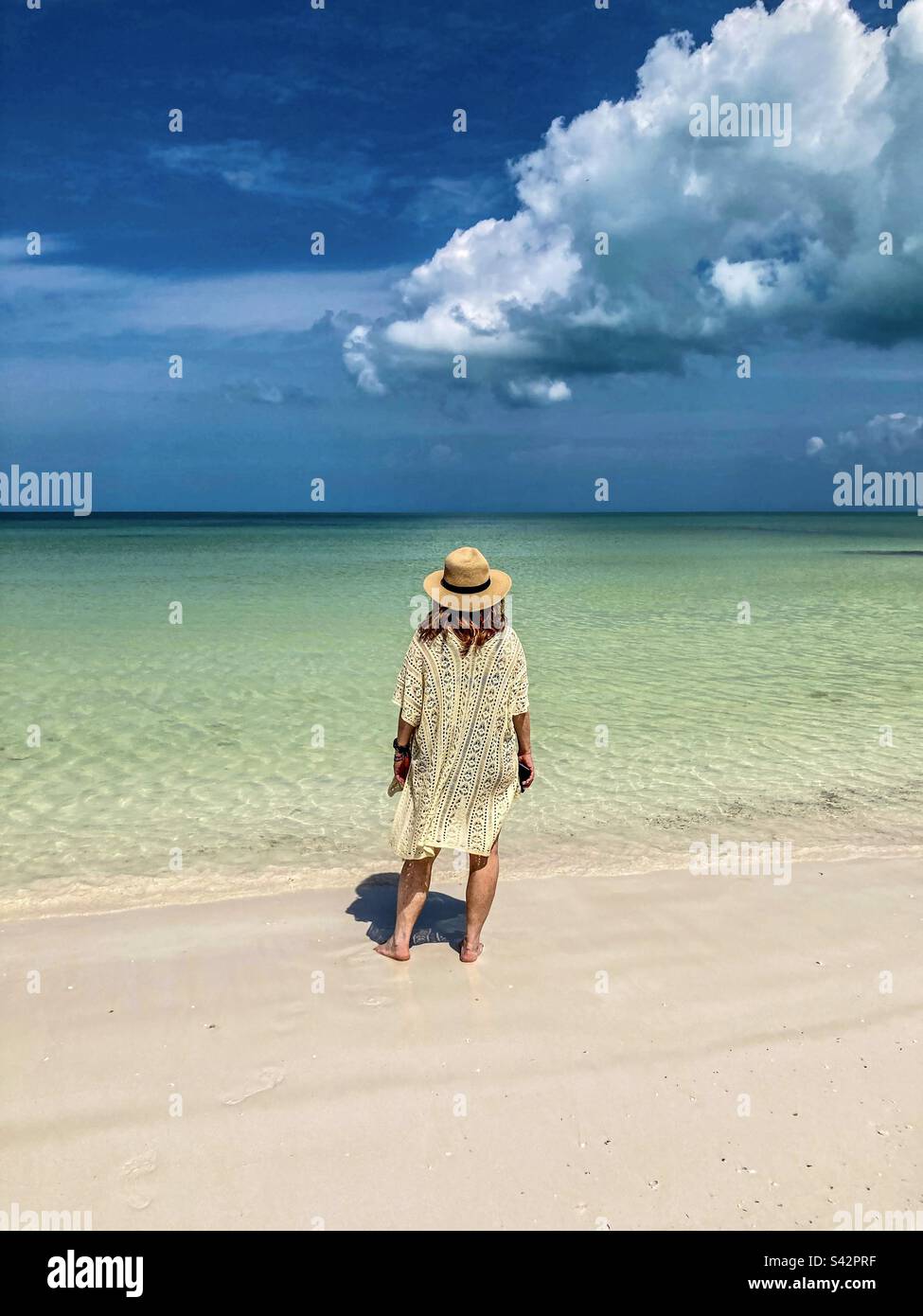 Eine wunderschöne Frau schaut vom Holbox Beach aus auf das faszinierende farbige Meer. - Smartphone-aufgenommenes Stockfoto