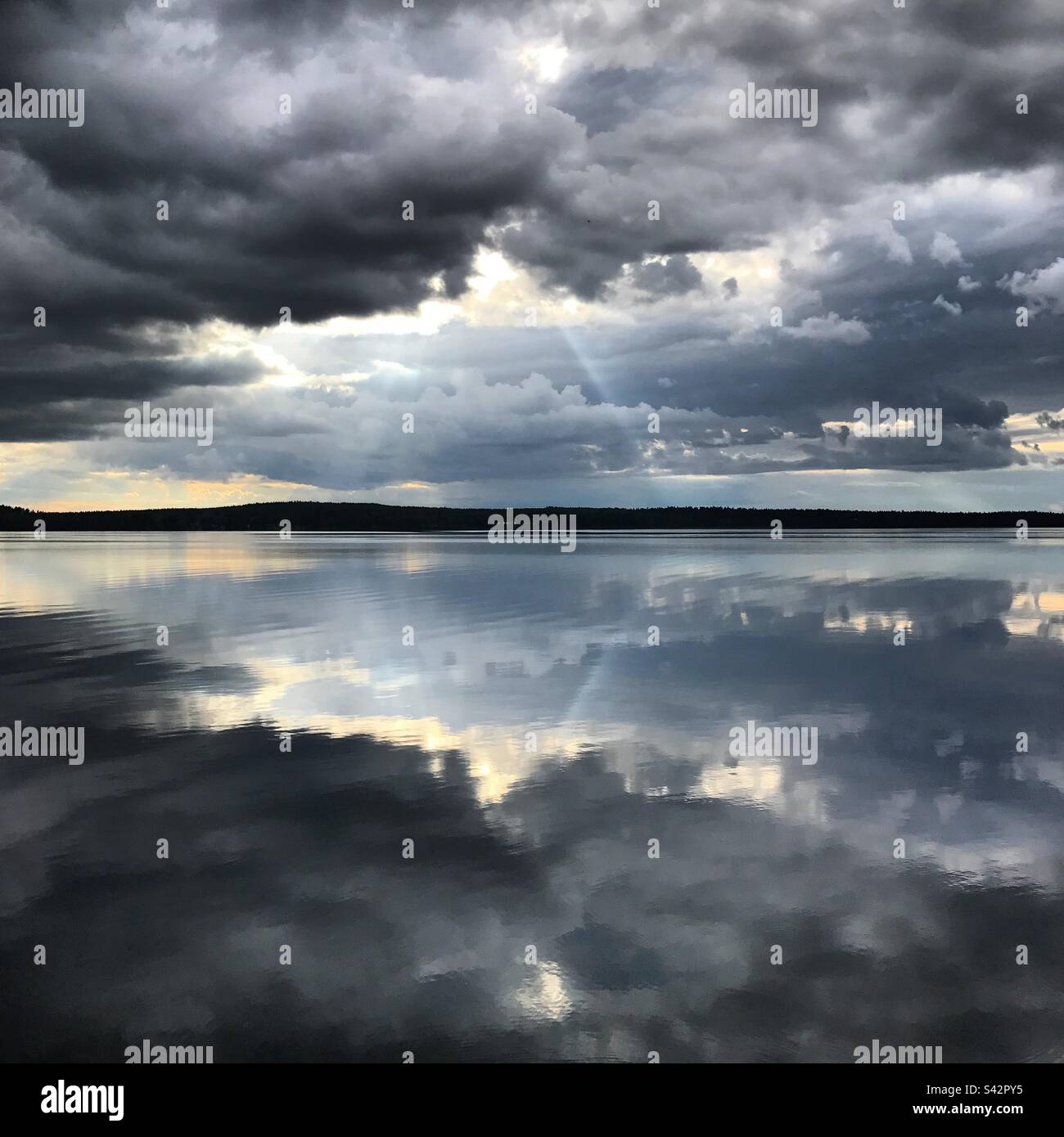 In einem arktischen Sommer spiegeln sich in einem großen See in der finnischen Kajaani-Region grüblende dunkle Sturmwolken wider Stockfoto