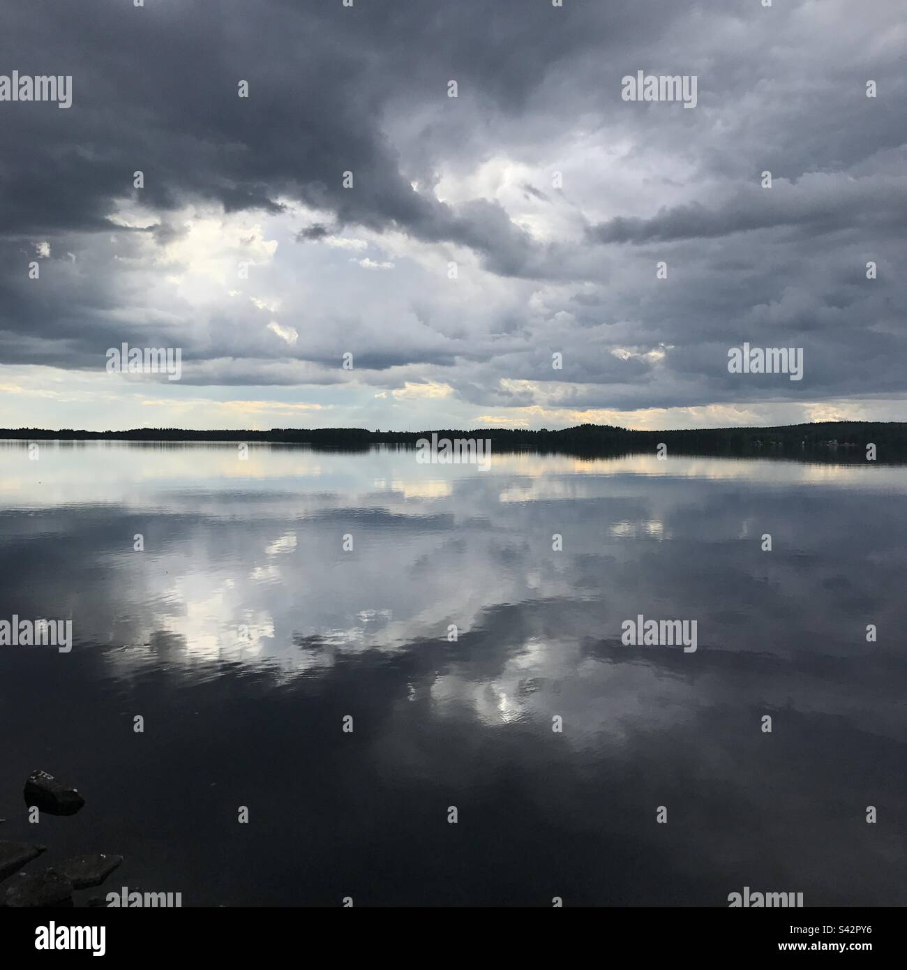 Grüblende dunkle Sturmwolken in einem großen See in der Kajaani-Region Finnlands während eines arktischen Sommers Stockfoto