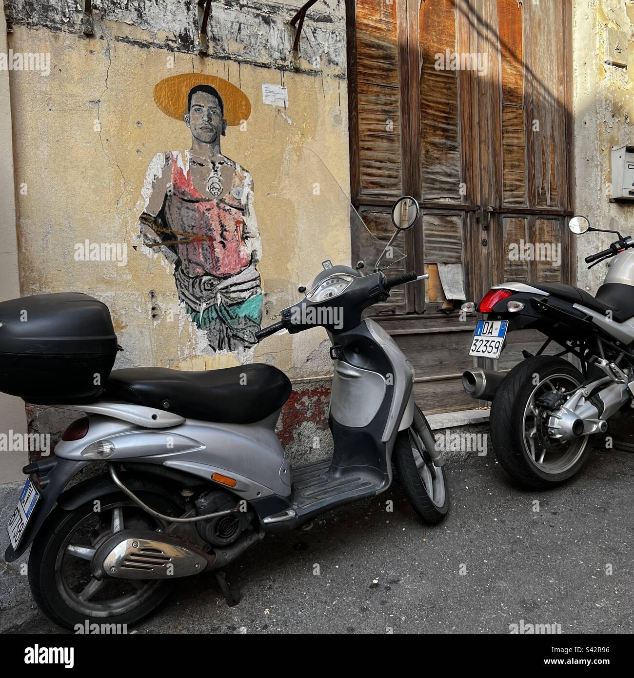 Motorroller stehen vor Straßenkunst und Holzläden in Taormina, Sizilien Stockfoto