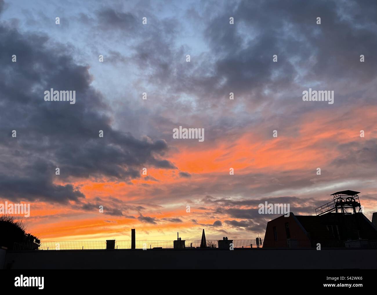Sonnenuntergang über dem Dach des Apartmentgebäudes in Berlin Deutschland. Wolken und lebendige Farben Stockfoto