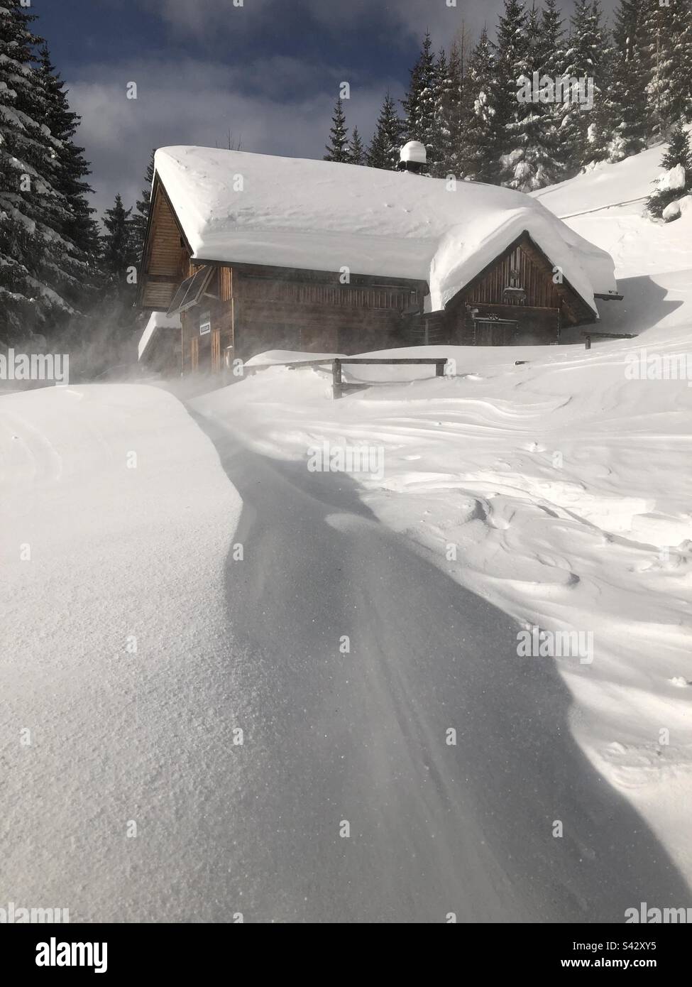 Schneebedeckte Holzhütte bei windigem Wetter - Smartphone-aufgenommenes Stockfoto