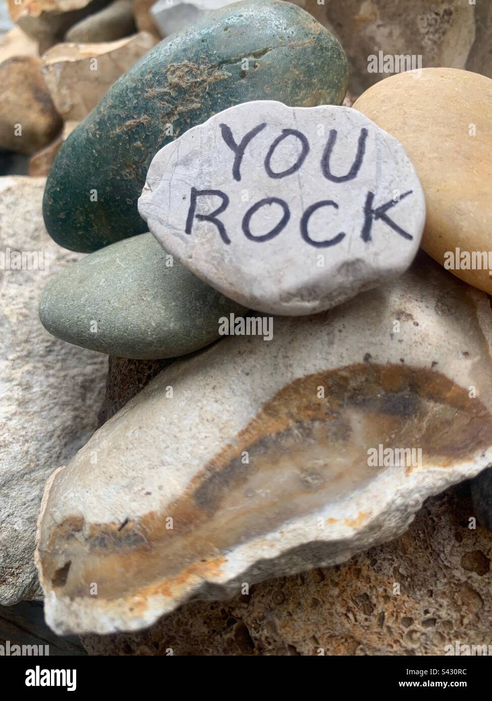 Motivationsfoto der Natur. Ein Haufen bunter und reich strukturierter Felsen mit der Aufschrift „YOU ROCK“ (DU ROCKST). - Smartphone-aufgenommenes Stockfoto