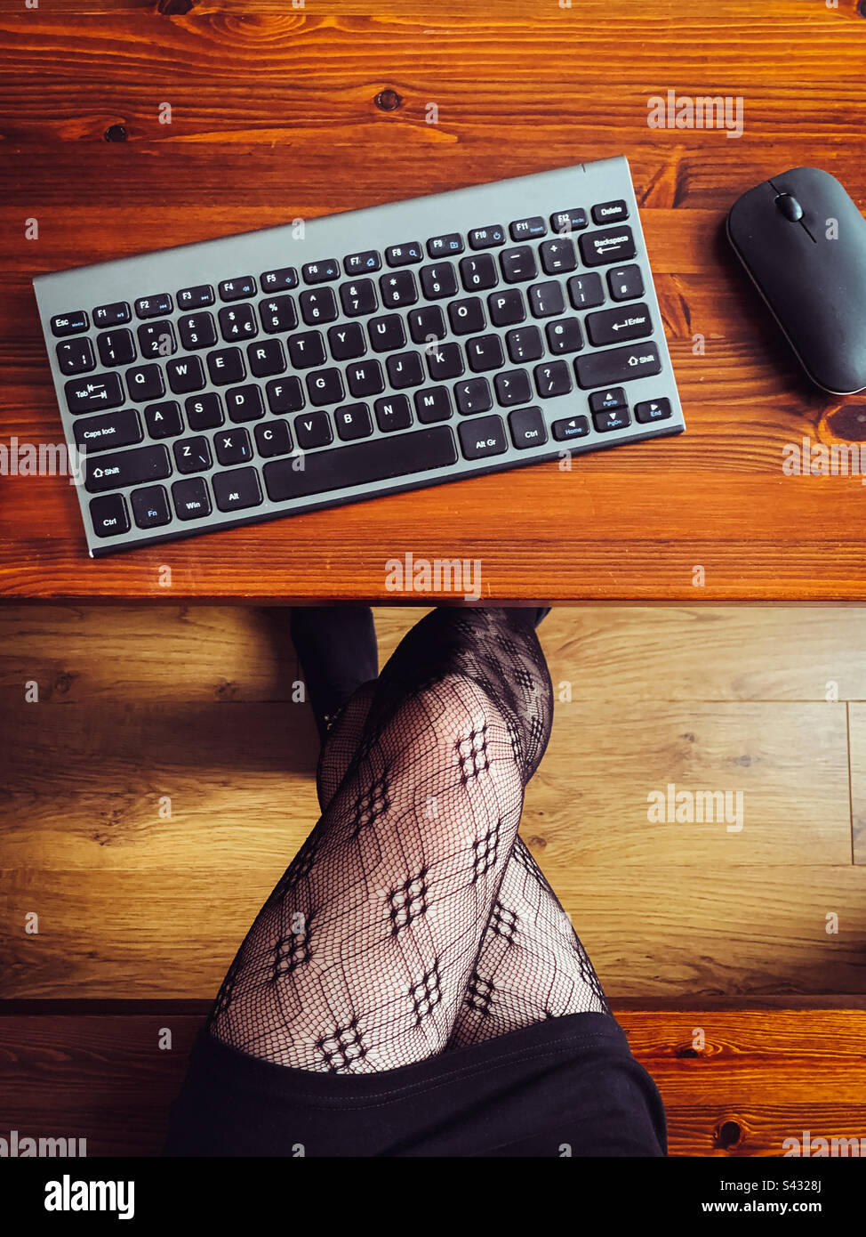 Draufsicht einer Frau, die mit Tastatur und Maus am Schreibtisch arbeitet - Smartphone-aufgenommenes Stockfoto