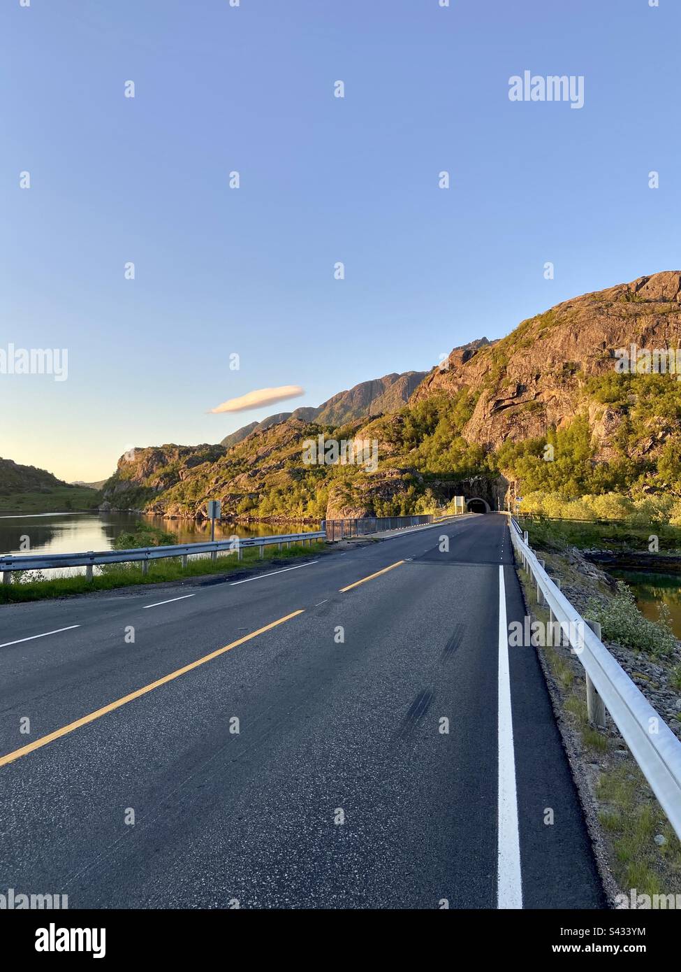 Asphaltstraße in den Tunnel auf den Lofoten-Inseln in Norwegen in einer sonnigen Sommernacht. - Smartphone-aufgenommenes Stockfoto
