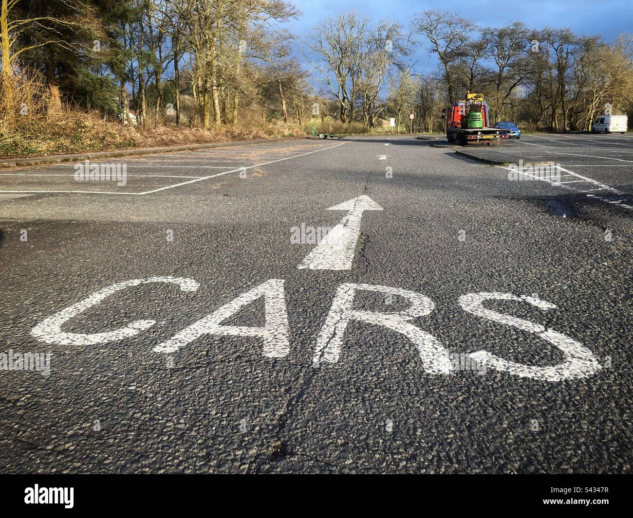 Ein Parkplatz mit einem Schild auf dem Asphalt, auf dem Autos stehen - Smartphone-aufgenommenes Stockfoto