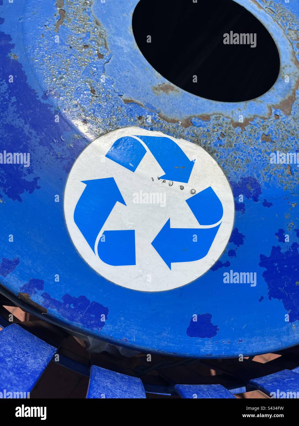 Nahaufnahme eines rostigen, hellblauen Recyclingbehälters mit Recycling-Symbol. Einschließlich Druckbereich. - Smartphone-aufgenommenes Stockfoto